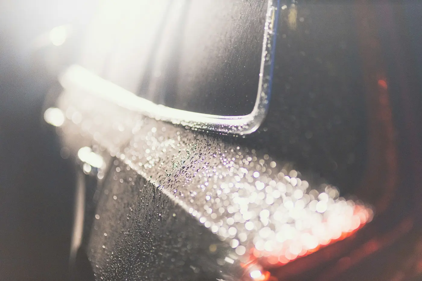 Water droplets beading on a glossy dark automotive surface