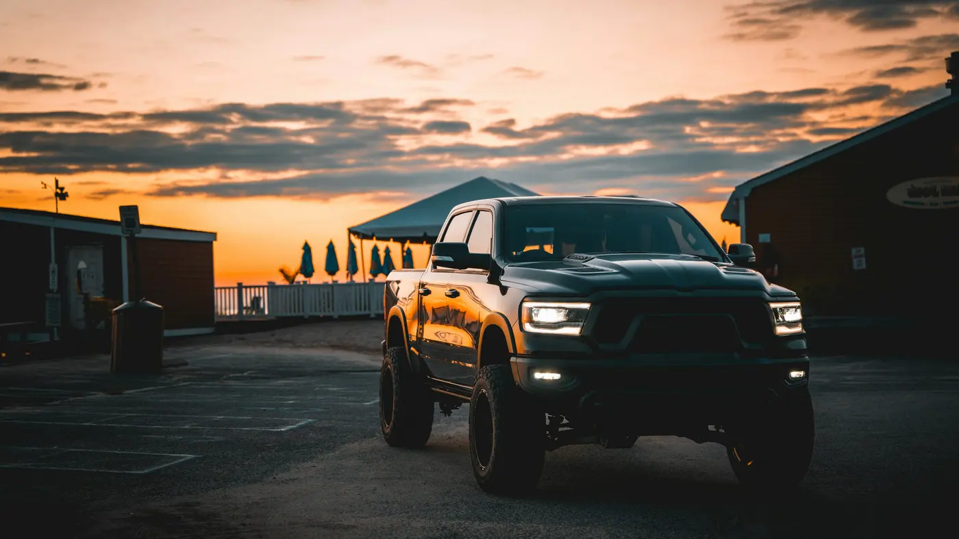 Black pickup truck with headlights on, parked at sunset