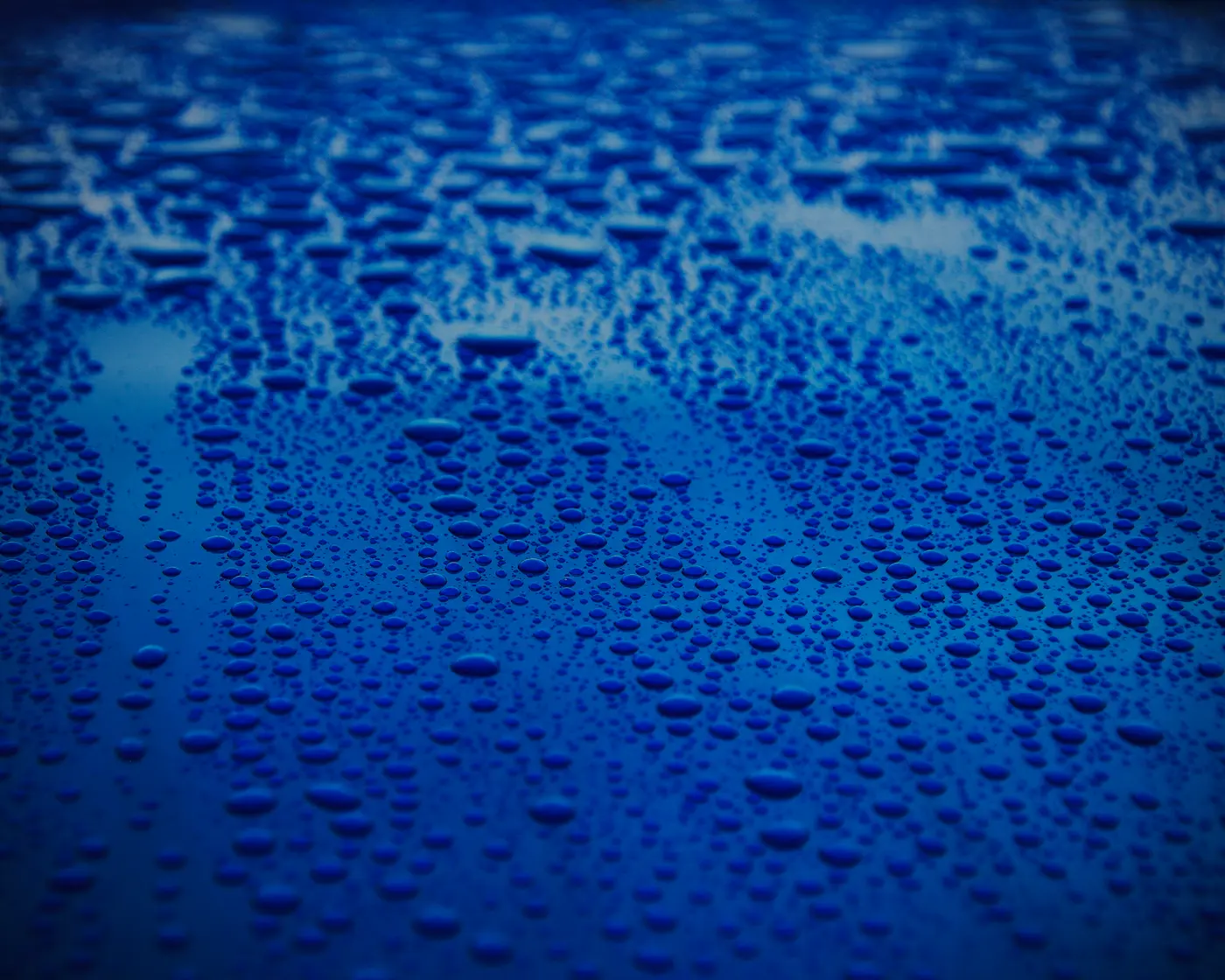 Water droplets across a deep blue painted surface