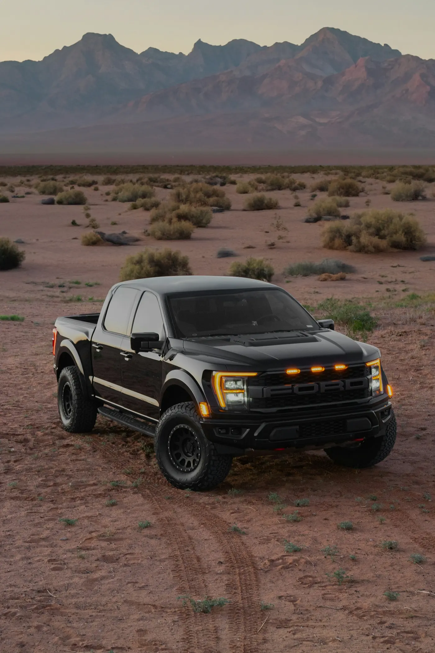 Black pickup truck with amber lights parked in a desert landscape