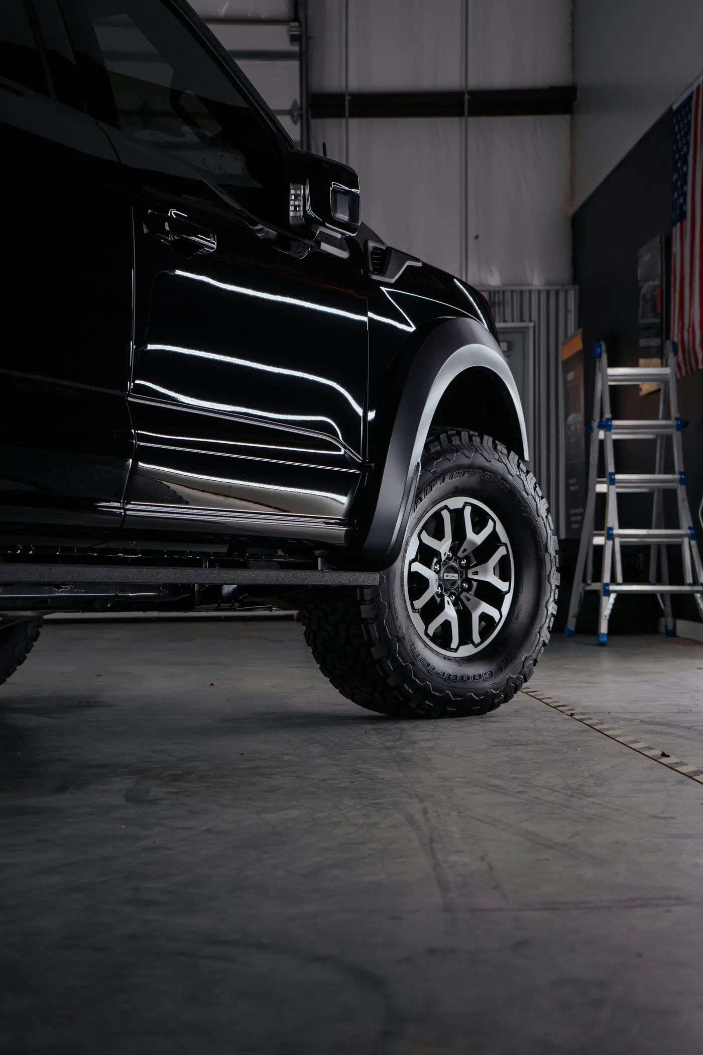 Black truck with a clean wheel and tire inside a garage