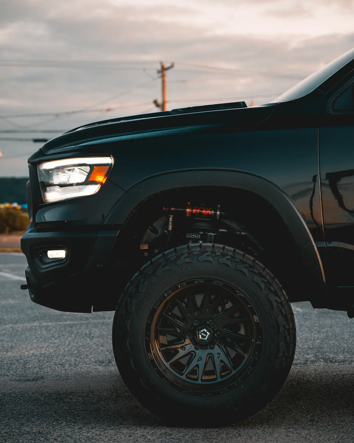 Close-up of a black pickup truck front fender, headlight and tire